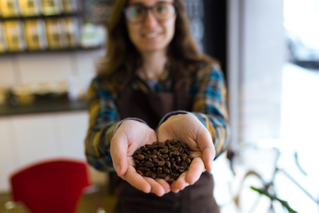 Portrait of beautiful young saleswoman holding coffee grains in organic shop.の写真素材