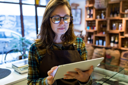 Portrait of beautiful young saleswoman using her digital tablet in organic shop.の写真素材