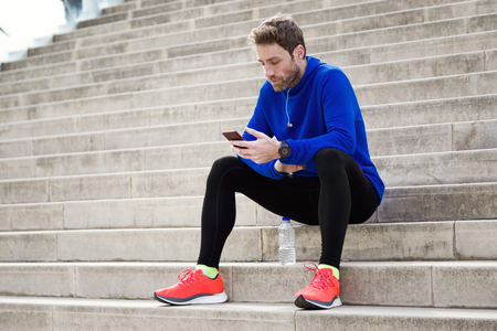 Portrait of sporty young man using his mobile phone in the street.