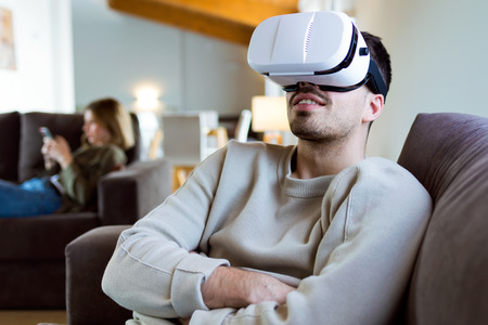 Portrait of handsome young smiling man using virtual reality headset at home.