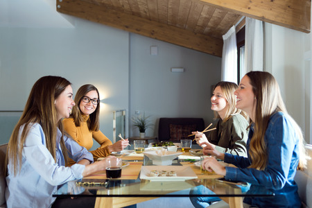 Portrait of four beautiful young women eating japanese food at home.の写真素材