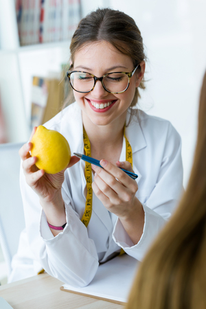 Shot of beautiful young dietician explaining to her patient the properties of the lemon in the consultation.の写真素材