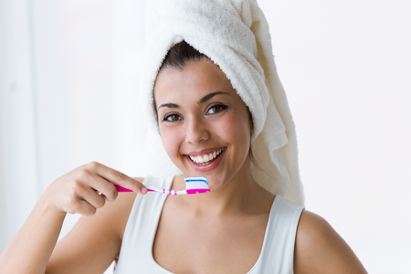Shot of pretty young woman brushing her teeth in the bathroom at home.の写真素材