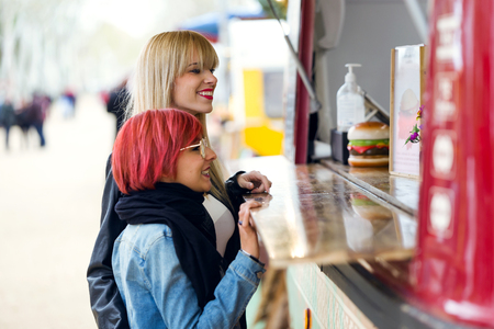 Shot of two beautiful young women visiting eat market in the street.の写真素材