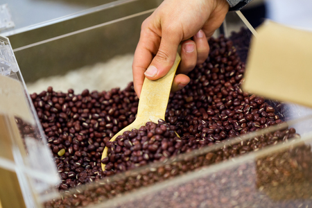 Close-up of saleswoman taking beans from a shopping bag in an organic store.