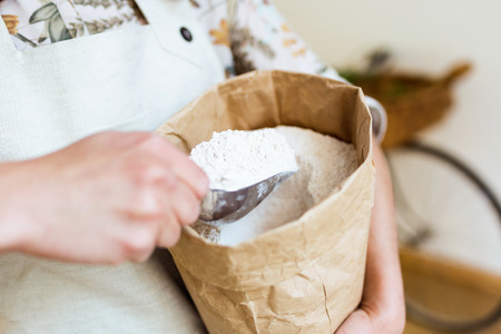Close-up of a saleswoman taking flour from a shopping bag in an organic store.