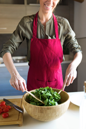 Close-up of young woman preparing salad in the kitchen.の写真素材