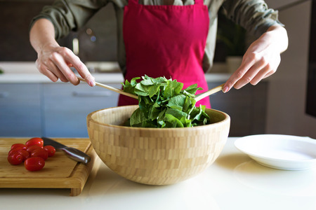 Close-up of young woman preparing salad in the kitchen.の写真素材