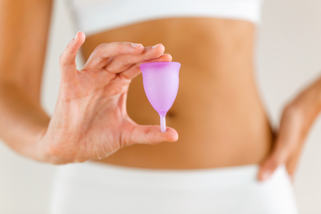 Close-up of young woman hands holding menstrual cup on the bathroom.の写真素材