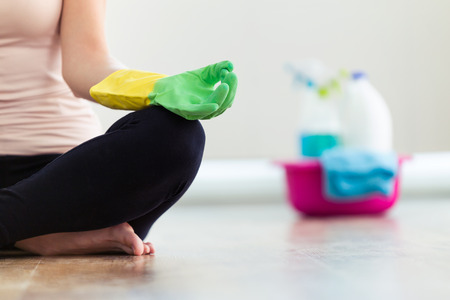 Close-up of young woman taking a break while cleanning the house. Lotus position.の写真素材