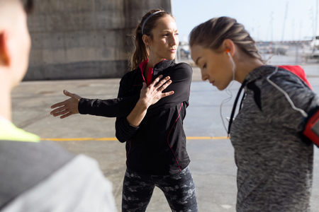 Portrait of two fit and sporty young women doing stretching in city.の写真素材