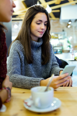 Portrait of beautiful young woman using her mobile phone at cafe shop.の写真素材