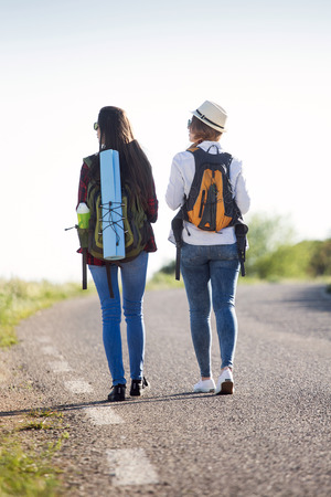 Portrait of two beautiful ladies hikers walking on the road.の写真素材