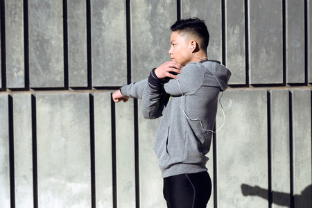 Portrait of fit and sporty young man doing stretching in city.