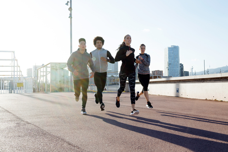 Outdoor portrait of group of friends running in the city.