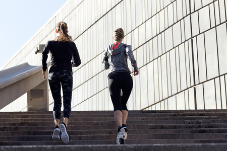 Portrait of two beautiful young women running in urban environment.の写真素材