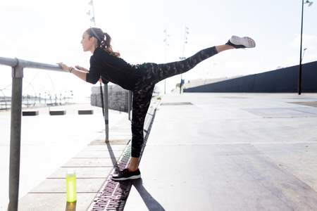 Portrait of fit and sporty young woman doing stretching in city.の写真素材
