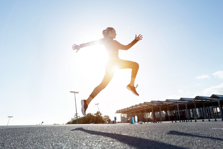 Portrait of beautiful young woman running in urban environment.の写真素材