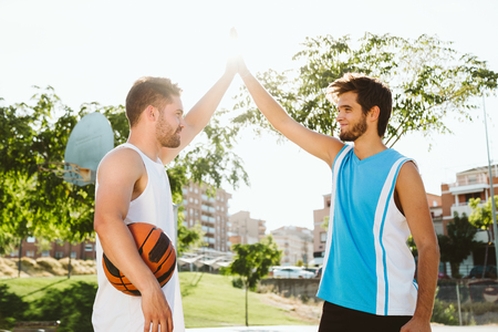 Outdoor portrait of two friends playing basketball on court.の写真素材