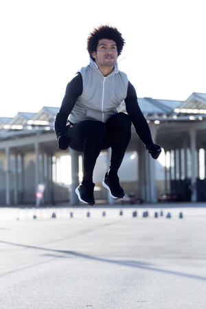 Portrait of fit and sporty young man jumping before run in the street.の写真素材