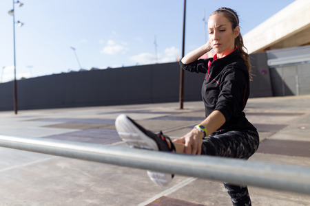 Portrait of fit and sporty young woman doing stretching in city.の写真素材