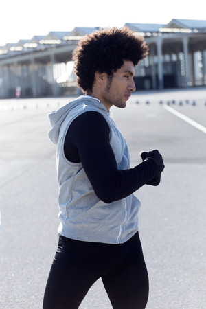Portrait of fit and sporty young man doing stretching in city.