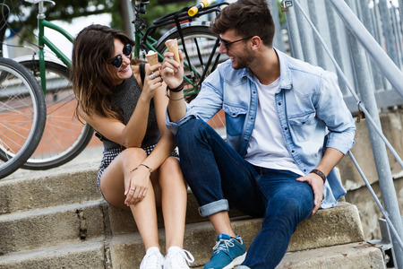 Portrait of happy young couple eating ice cream in the street.