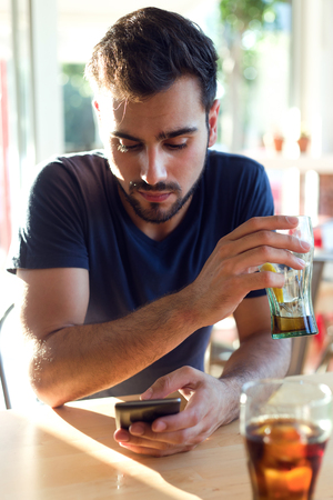Portrait of modern young man with mobile phone in cafe.の写真素材
