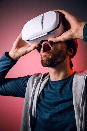 Portrait of handsome young man using virtual reality headset. Isolated on red.の写真素材