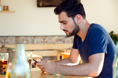 Portrait of modern young man with mobile phone in cafe.の写真素材