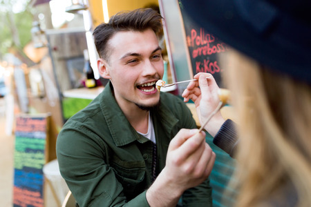 Portrait of beautiful young couple visiting eat market in the street.の写真素材