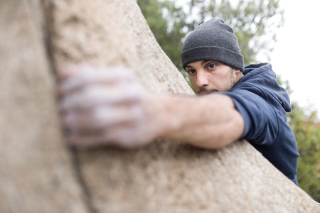 Portrait of handsome young man climbing natural rocky wall.