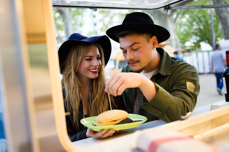 Portrait of beautiful young couple visiting eat market in the street.の写真素材