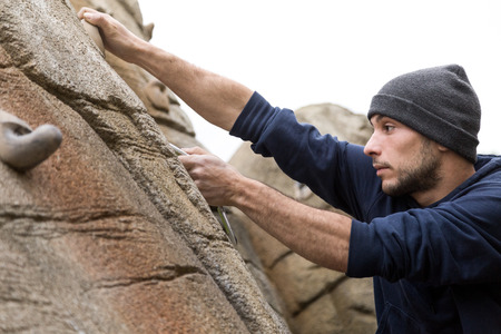Portrait of handsome young man climbing natural rocky wall.