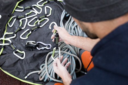 Portrait of young man preparing the equipment for climbing.