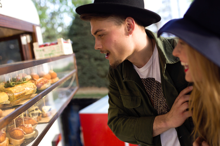 Portrait of beautiful young couple visiting eat market in the street.の写真素材