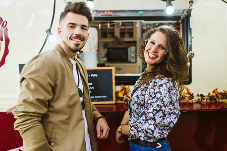 Portrait of beautiful young couple visiting eat market in the street.