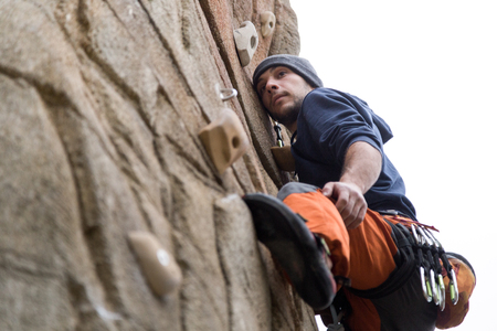 Portrait of handsome young man climbing natural rocky wall.