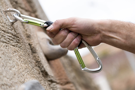 Close-up of man's hand on handhold on natural rocky wall.