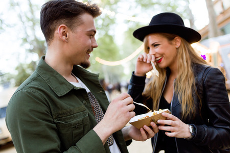 Portrait of beautiful young couple visiting eat market in the street.の写真素材