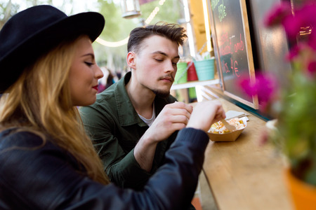 Portrait of beautiful young couple visiting eat market in the street.の写真素材