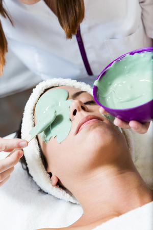 Portrait of beautiful young woman with antiaging facial mask in spa.の写真素材