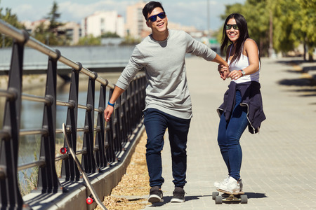 Portrait of young couple skateboarding in the street.の写真素材