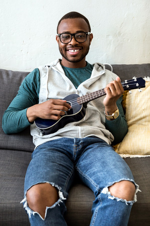 Portrait of handsome young black man playing the guitar at home.の写真素材