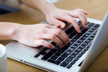 Close up of young woman working with laptop at home.