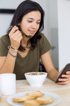 Portrait of beautiful young woman enjoying breakfast at home.の写真素材