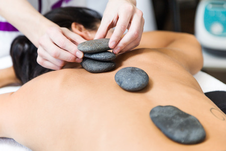 Portrait of beautiful young woman with hot stones in beauty spa.の写真素材