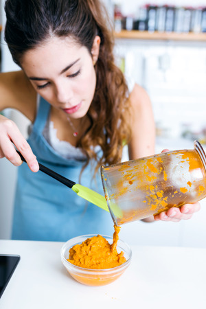 Portrait of beautiful young woman serving mashed vegetables in a bowl.の写真素材