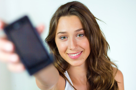 Portrait of beautiful young woman at home with mobile.の写真素材