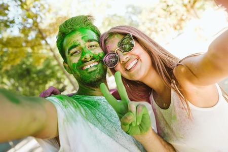 Portrait of beautiful young couple playing in the park on holi colours festival.
